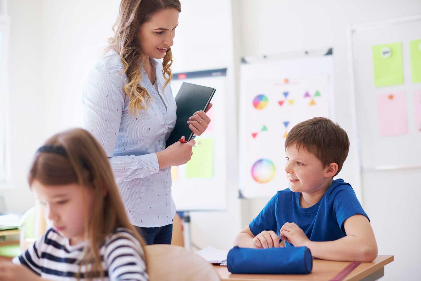 Teacher smiling at schoolboy in class